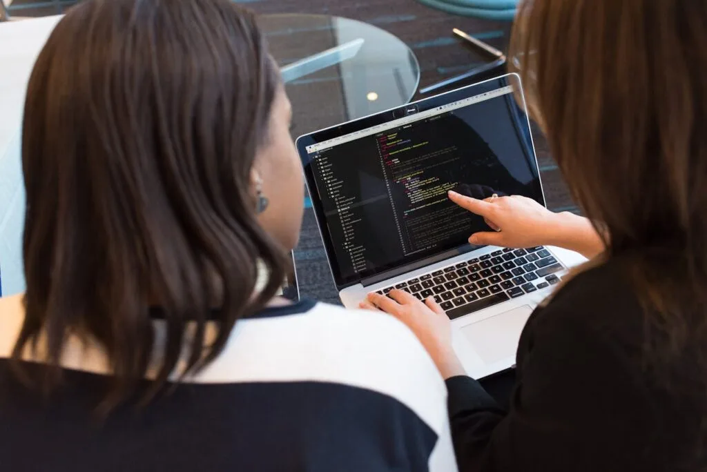 Two women coding on a computer.