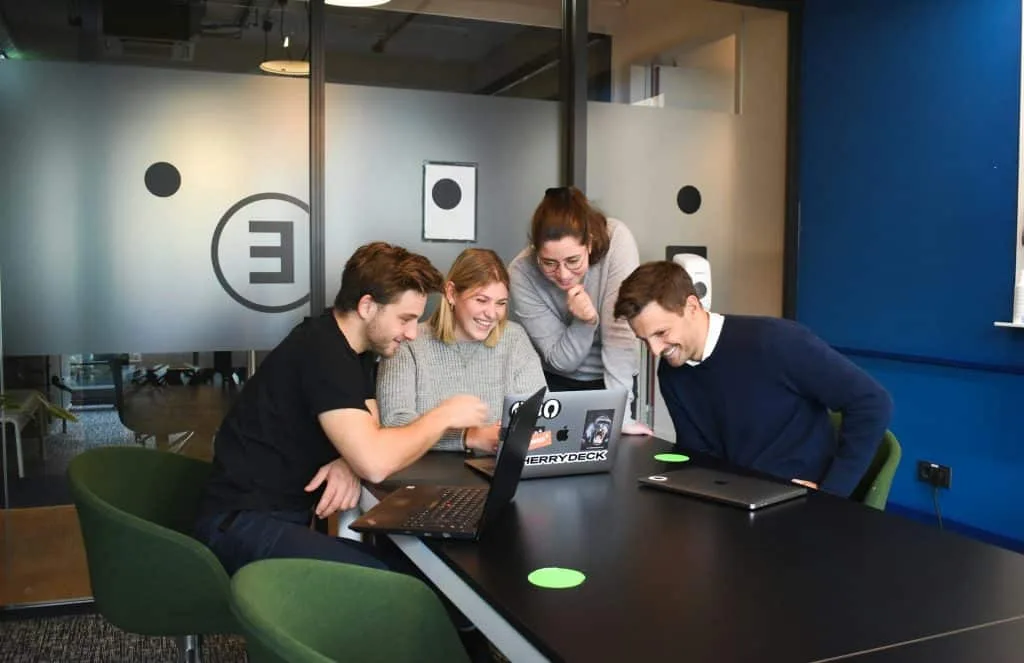 Four people on a meeting room looking at the laptop