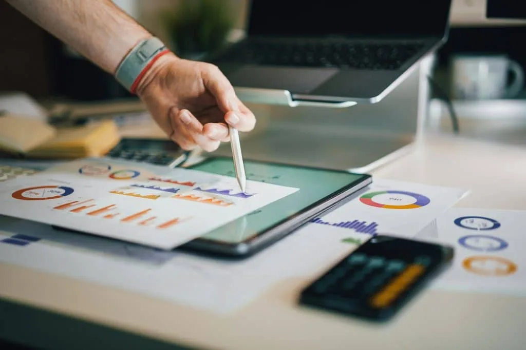 A hand pointing at a sheet of paper displaying graphics and analytical data.