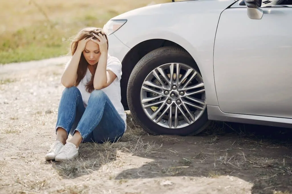 worried looking lady sitting right next to a car
