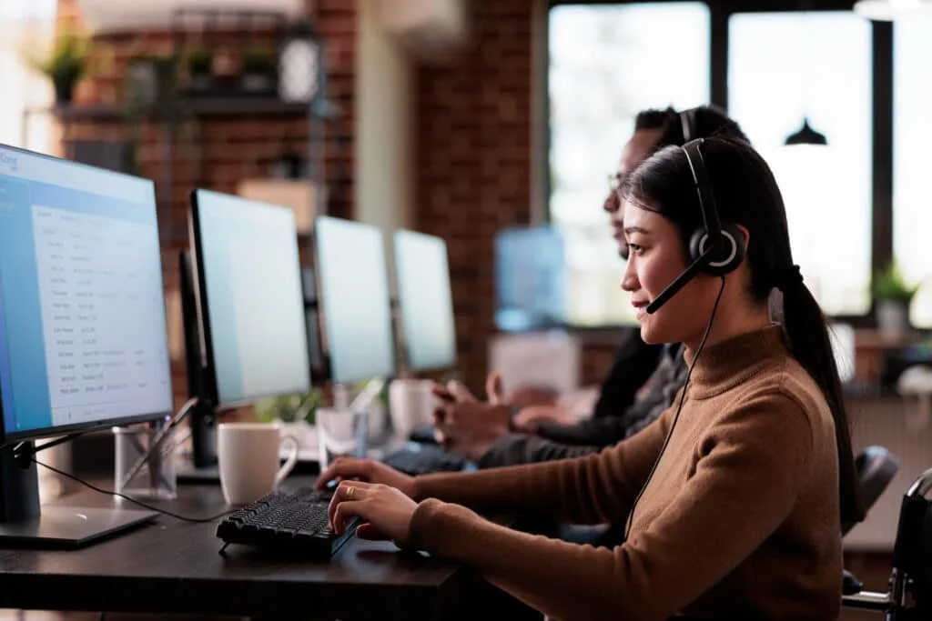 a woman working on a computer while using a headset 