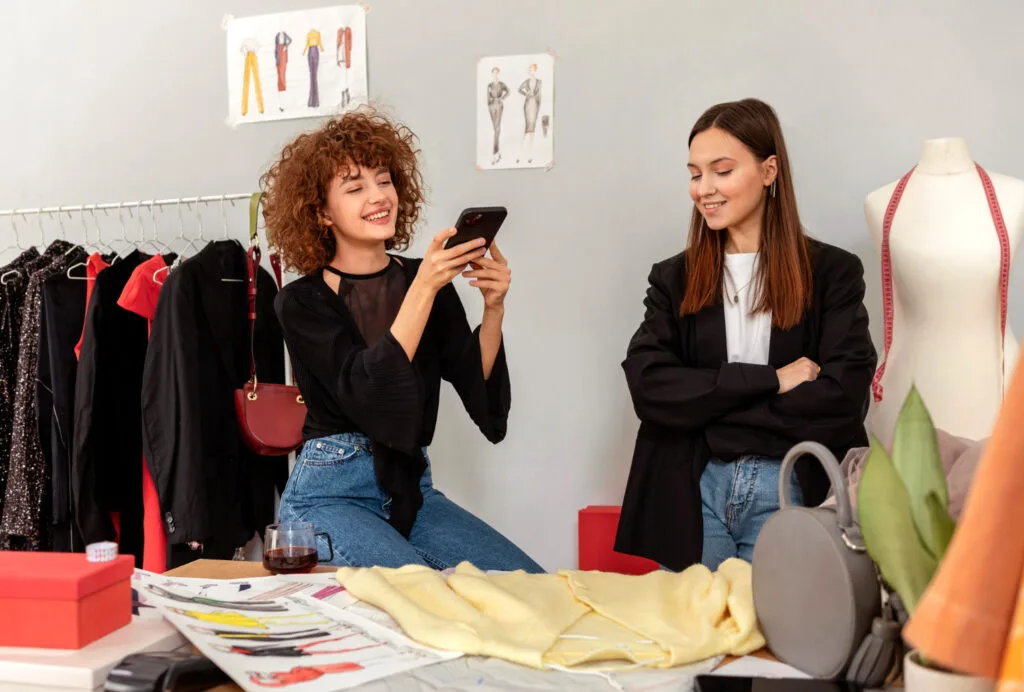two women taking picture of fashion clothing