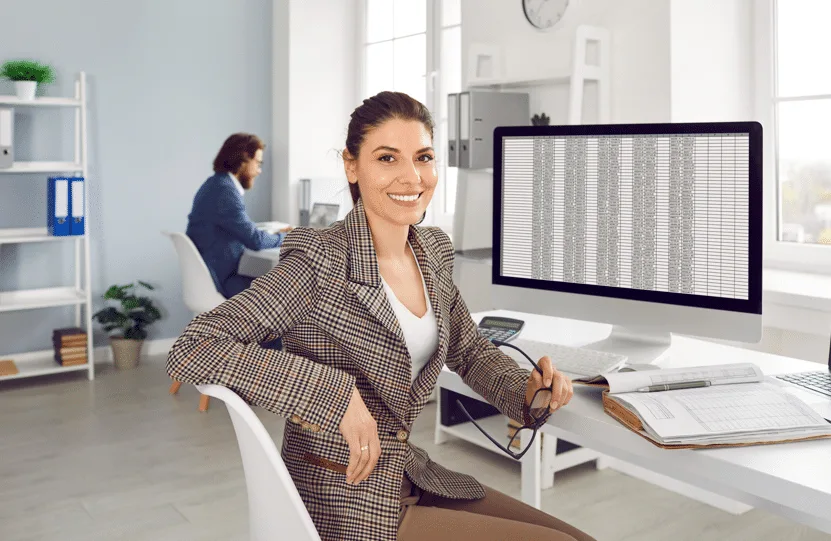 A woman dressed in a checkered suit seated in an office.